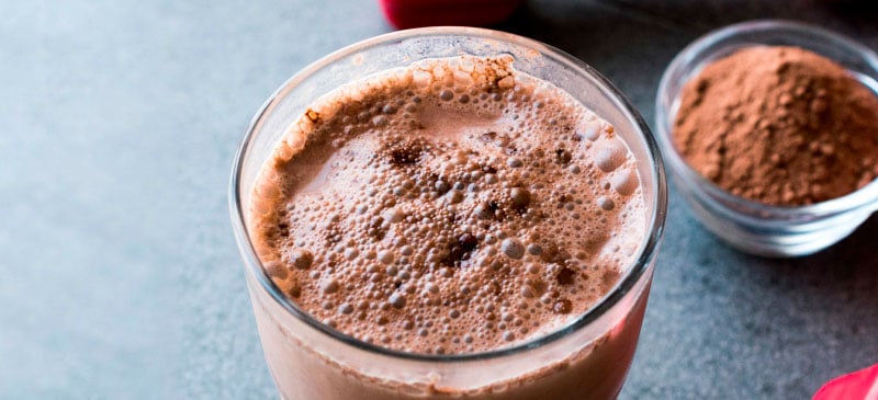Whey protein powder in a glass jar with a scoop beside it