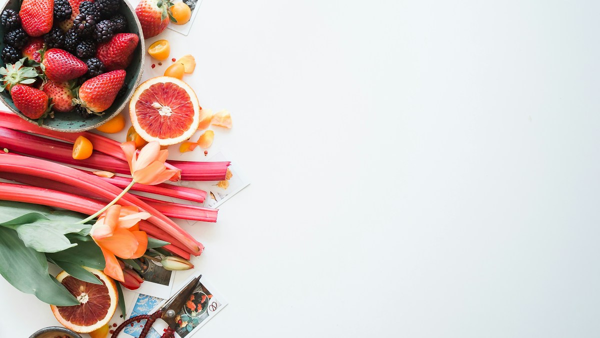 Text-free bright arrangement of fresh citrus, berries, and colorful plant foods on a light surface for an aloe vera juice wellness guide