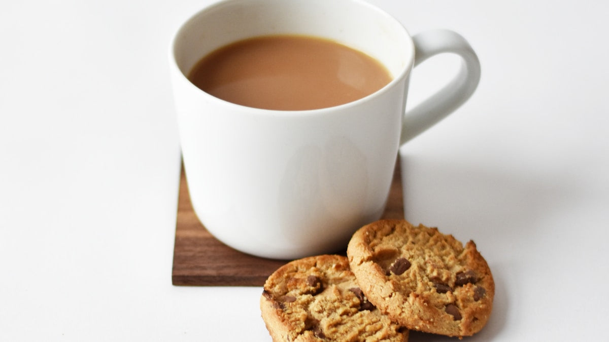 Warm morning drink in a white mug on a wooden coaster for a gentle daily wellness routine