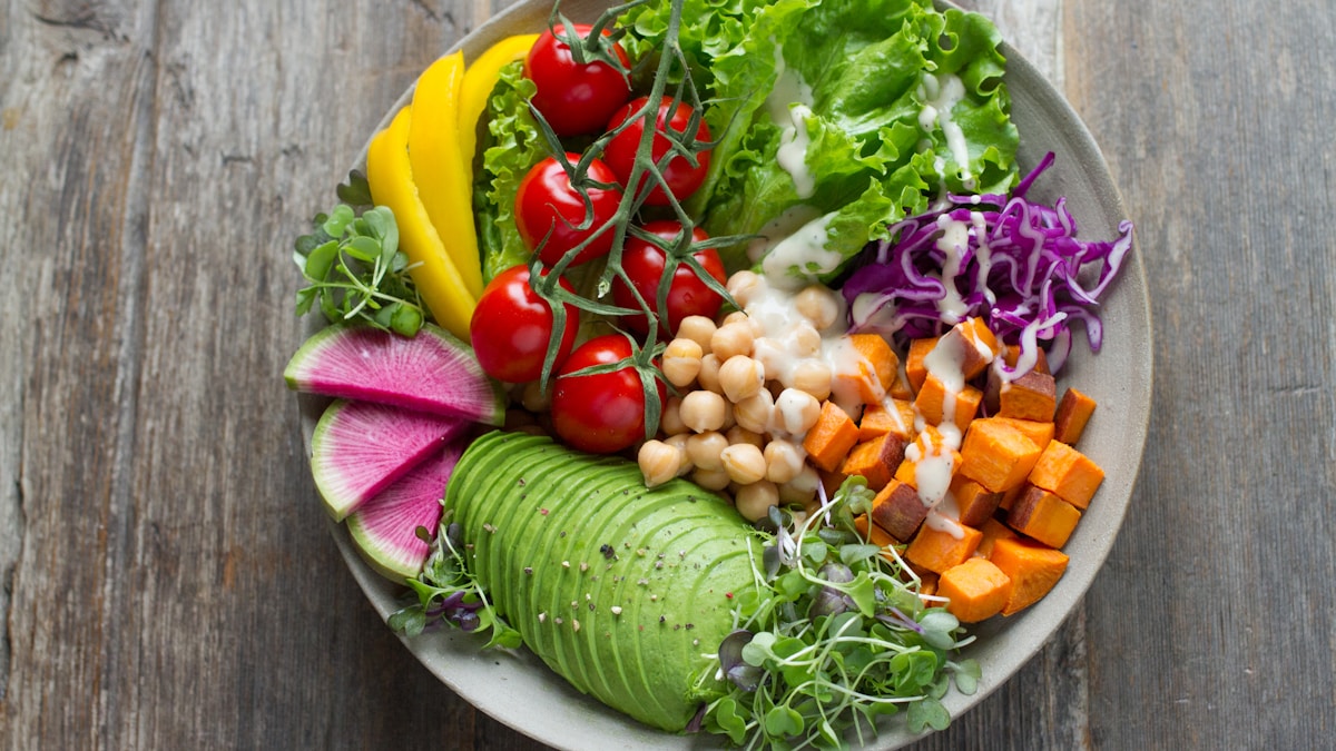 Text-free overhead view of a colorful whole-food bowl with avocado, tomatoes, chickpeas, sweet potato, and greens for a proprietary blend supplement label guide